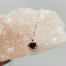 Load image into Gallery viewer, raw silver garnet heart silver necklace displayed on a piece of rose quartz
