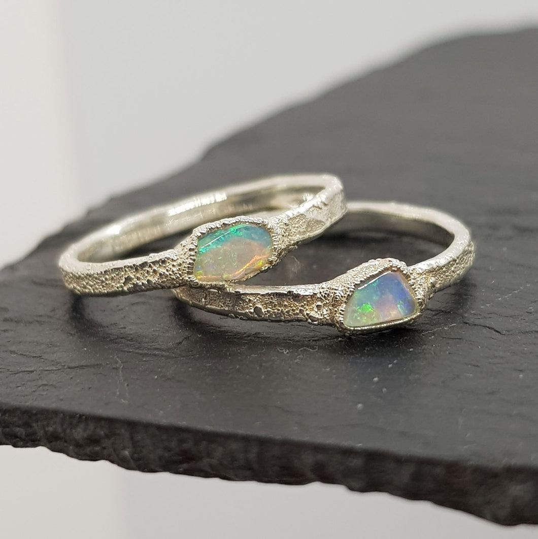 raw opal textured silver rings displayed on slate