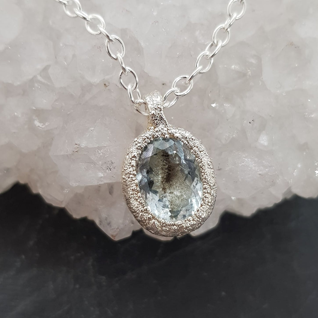 salt and pepper aquamarine raw silver necklace displayed on a crystal